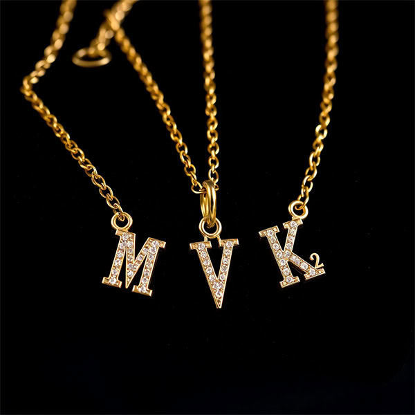 585er Goldkette mit Zirkonia - Eine luxuriöse Goldkette mit funkelnden Zirkonia-besetzten Initialen auf dunklem Samt.